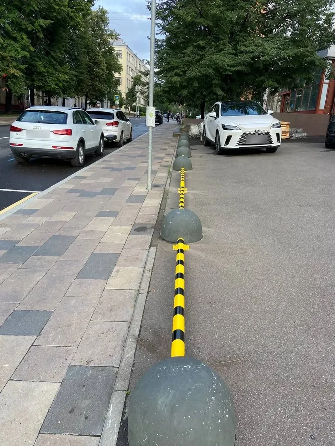 Kerbside rail between concrete bollards on a pavement